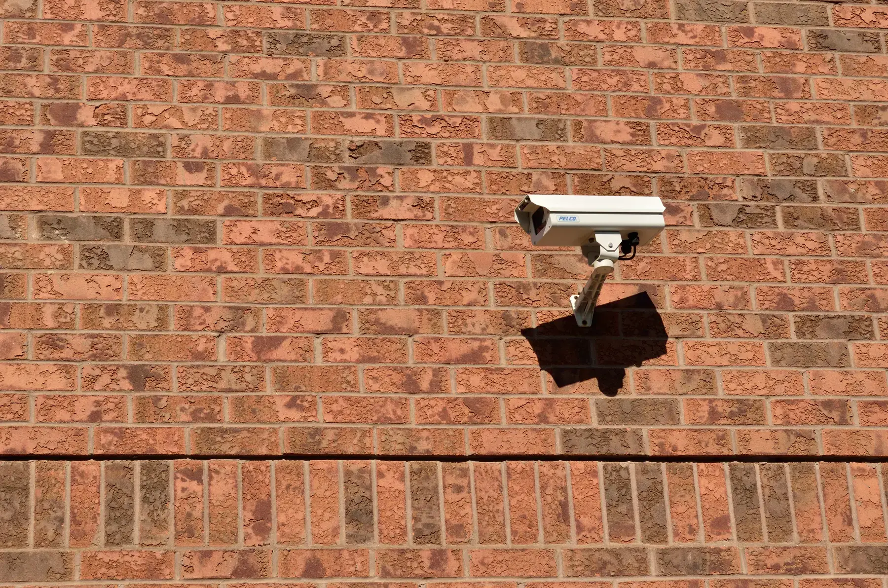 Illustrative outdoor security camera mounted on a brick wall