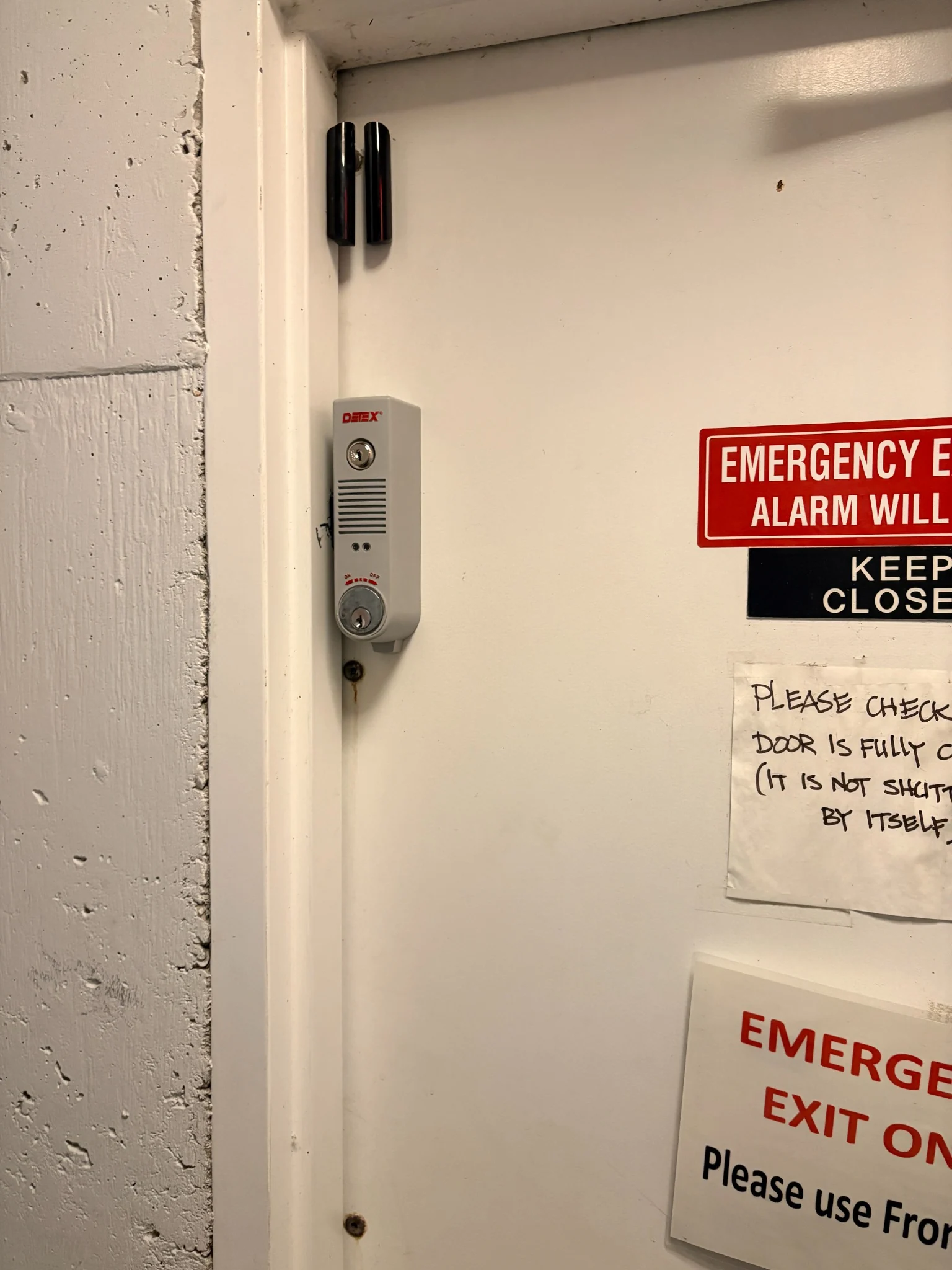 Detex local door alarm and separate black Ajax sensor fitted to the second parkade exit door at The Calladine in Vancouver