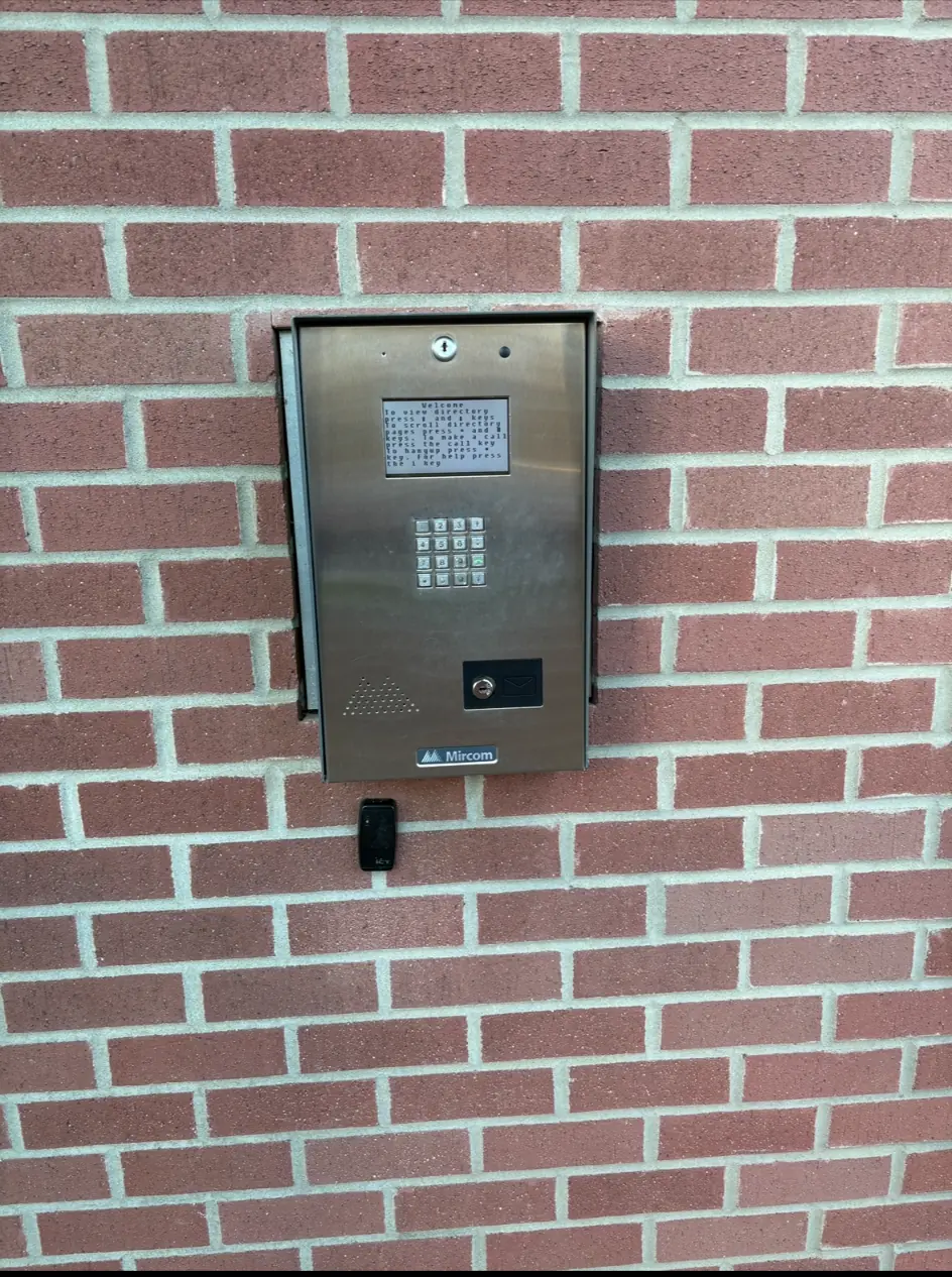 Before photo of the old Mircom keypad intercom on the brick entrance wall at Thurston Apartments in Chilliwack