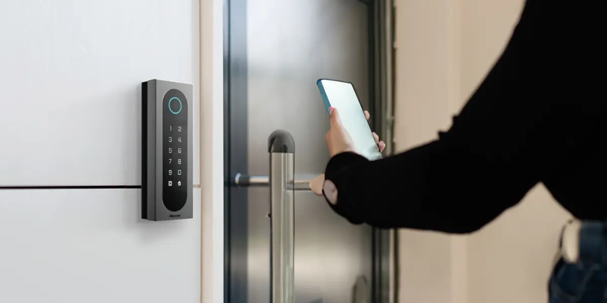 Resident using a smartphone at an access-control reader beside a building entrance
